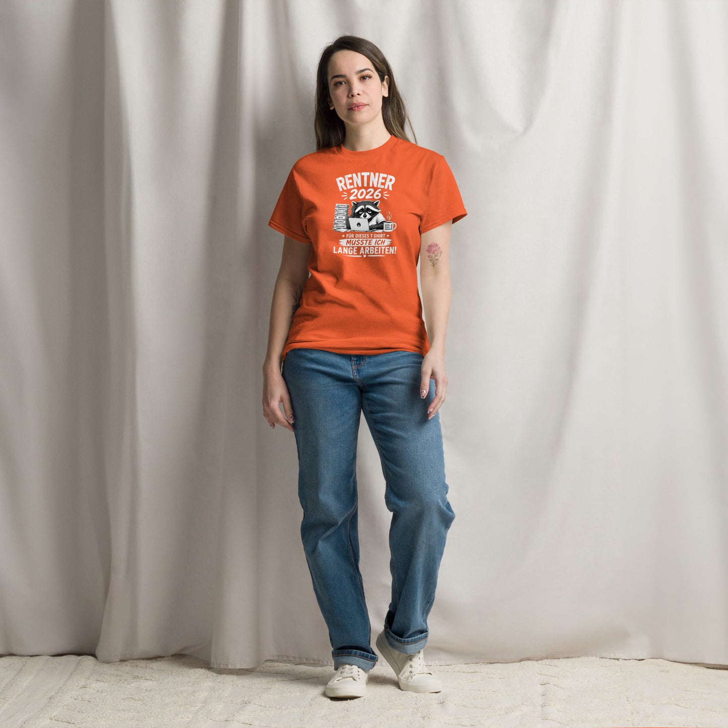 „Oranges T-Shirt mit lustigem Rentner-2026-Motiv, müdem Waschbären am Laptop, Papierstapel und Kaffeetasse sowie dem Spruch ‚Für dieses T-Shirt musste ich lange arbeiten!‘“